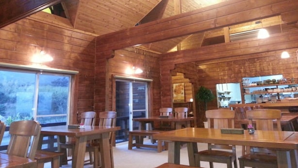 Un intérieur rustique en bois, avec de hauts plafonds et un coin repas doté de tables et de chaises en bois.
