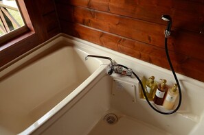 Eine Badewanne mit Duschbrause und drei Seifenflaschen.