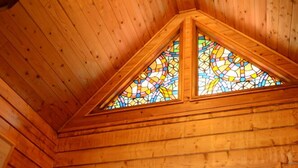 Une cabane en bois avec une porte sombre, une petite fenêtre et une étagère en bois sur laquelle sont posés divers objets.