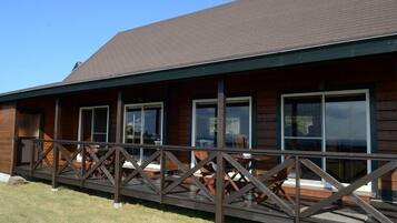 A wooden cabin with a covered deck and large windows.