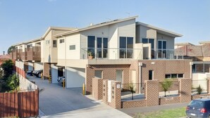 A modern two-story residential building with a flat roof, large windows, and a brick facade.