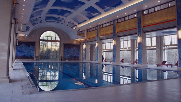 Une grande piscine intérieure dotée d’un haut plafond et de grandes fenêtres.