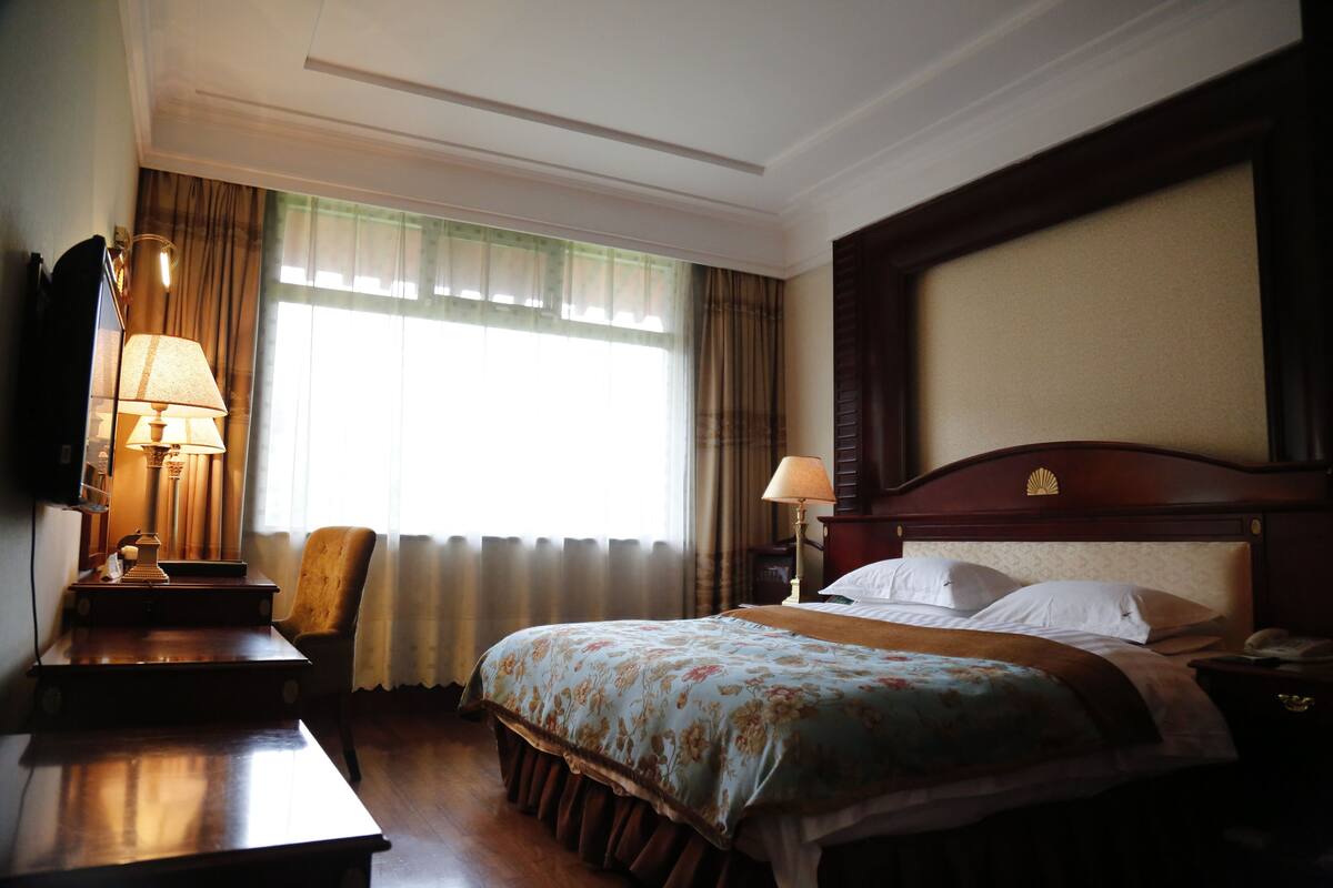 Ein Hotelzimmer mit Bett, Schreibtisch, Stuhl, Lampe und Nachttisch.