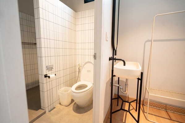 A bathroom with a toilet, a sink, and a shower area.