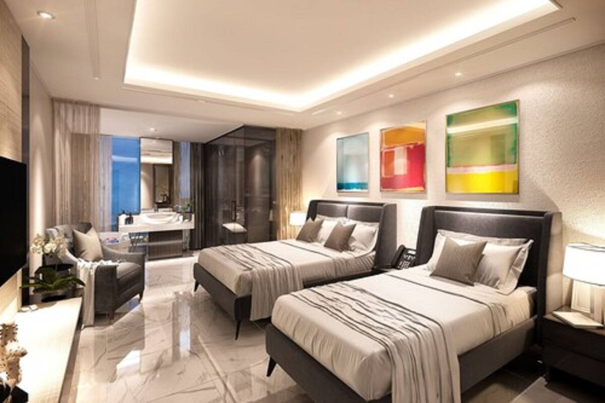 Une chambre d’hôtel moderne avec deux lits, un coin salon, une salle de bain avec un meuble-lavabo et des œuvres d’art aux murs.