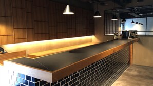 Una cocina moderna con armarios de madera, encimera negra y lámparas colgantes.