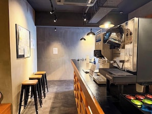 A coffee shop interior with a counter, espresso machine, stools, and a wall with papers. - Congrats Hotel Kyoto (Kyoto)