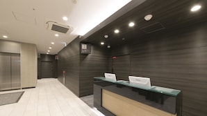 Un espace d’accueil moderne avec un comptoir en verre, un bureau d’accueil et une enseigne fixée au mur indiquant le numéro de la salle : 2.