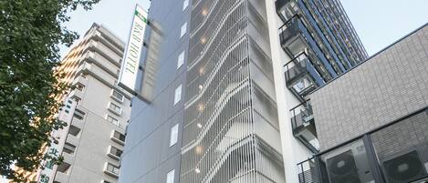 Un hôtel moderne, avec une entrée imposante, de nombreux étages et un balcon bien visible aux niveaux supérieurs.