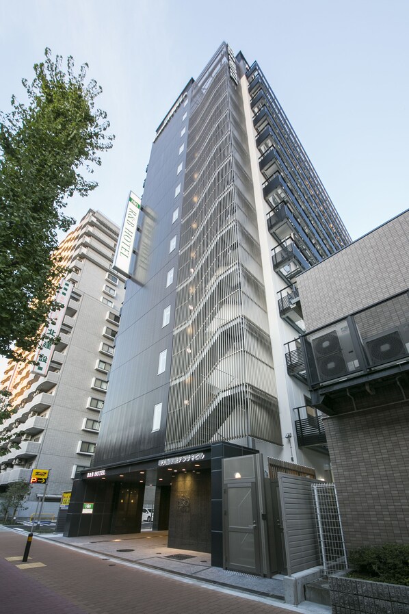 Un hôtel moderne, avec une entrée imposante, de nombreux étages et un balcon bien visible aux niveaux supérieurs.