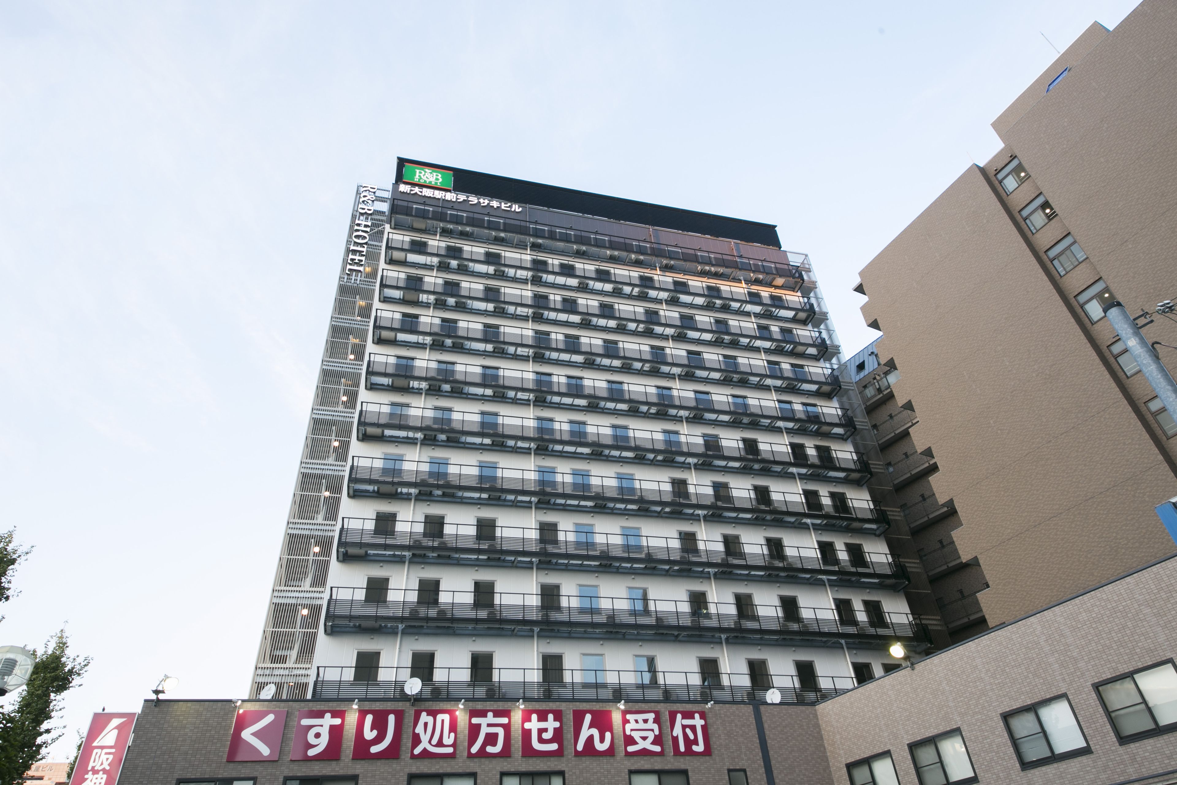 A multi-story hotel with a modern design, featuring a prominent sign at the top and a red sign at the bottom.
