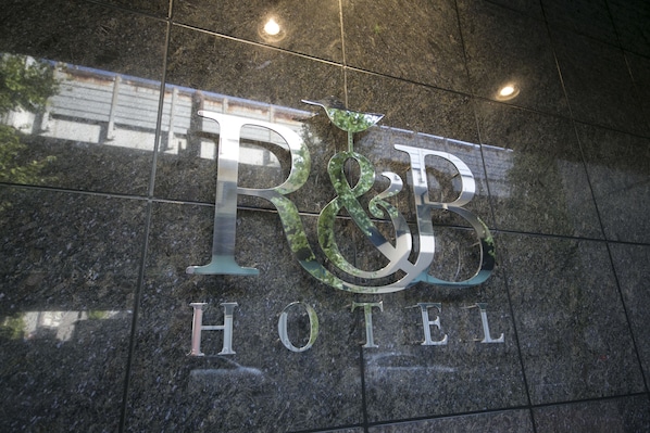 Un letrero de granito pulido con el logotipo y el nombre del Hotel R&B.