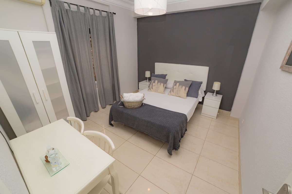 Un dormitorio con cama, mesitas de noche, un escritorio y una silla.