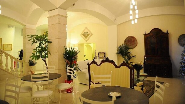 A spacious living area with a high ceiling, a dining table, and several chairs. There is a staircase leading to another level, and a large wooden cabinet is visible. - Le Dodici Lune (Montecorvino Rovella)