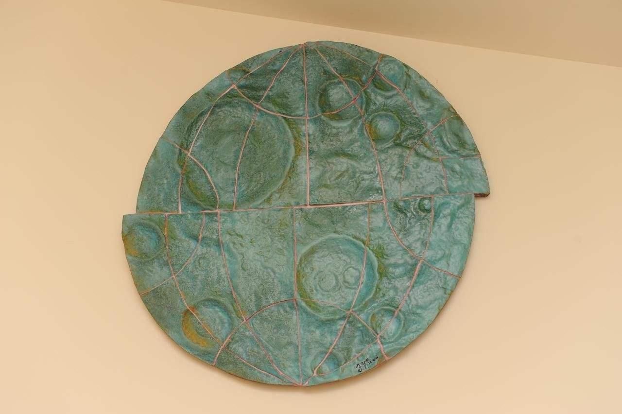 Een rond kunstwerk met een reliëf oppervlak en een rasterpatroon.