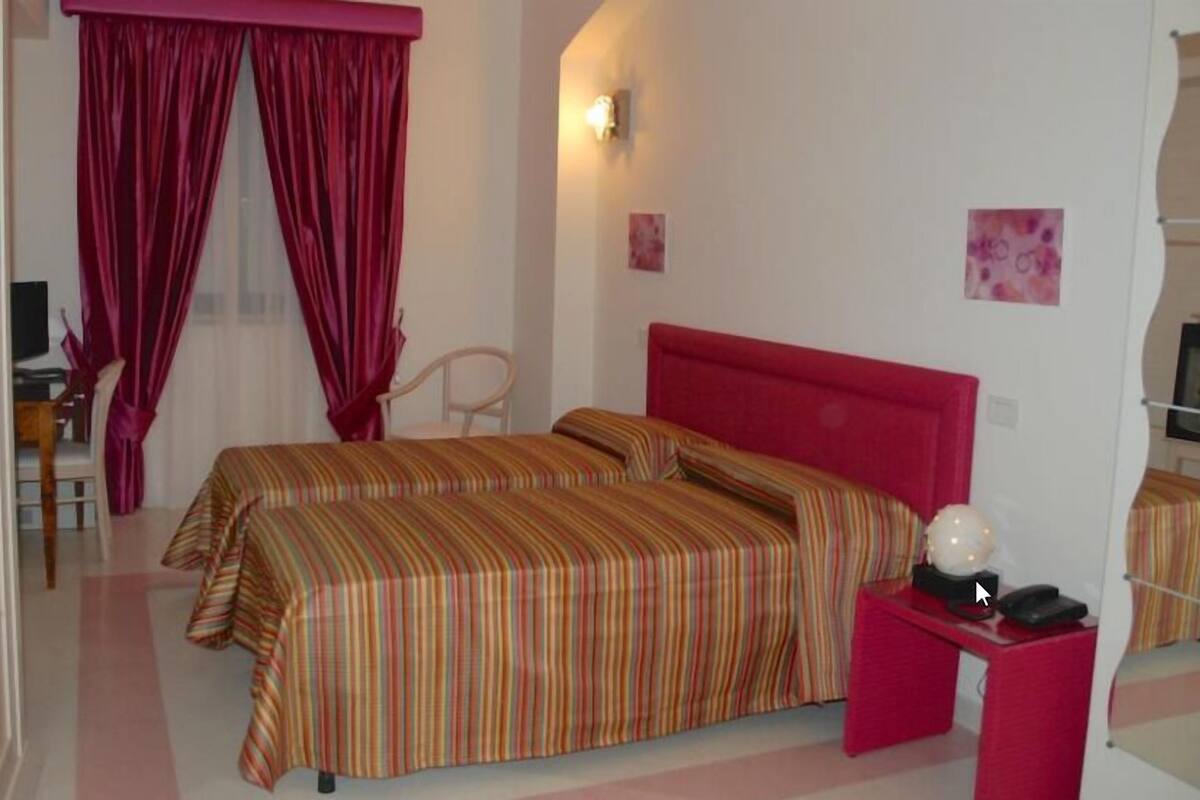A room with two beds, a desk, a chair, and a globe on the nightstand.