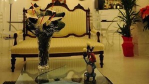 A room with a sofa, a glass coffee table, a vase with flowers, a small figurine, and a wall with circular decorations. - Le Dodici Lune (Montecorvino Rovella)