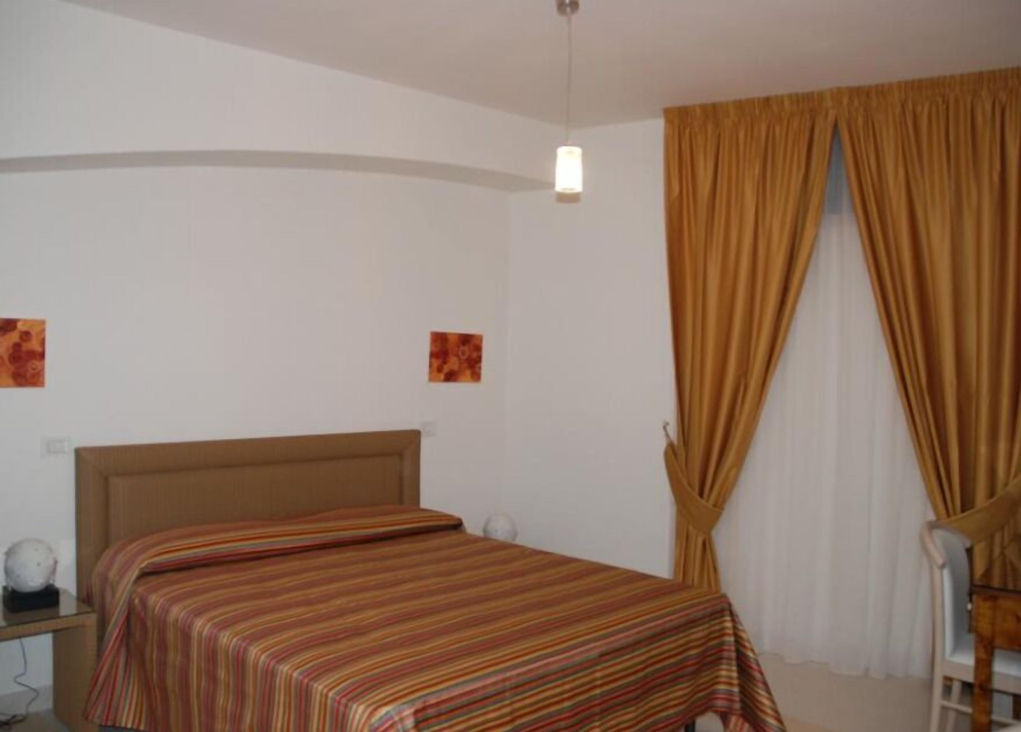 A bedroom with a bed, a chair, and curtains.