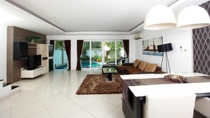Una sala de estar moderna con una televisión de pantalla plana, un sofá, una mesa de centro y un comedor con una mesa y sillas.