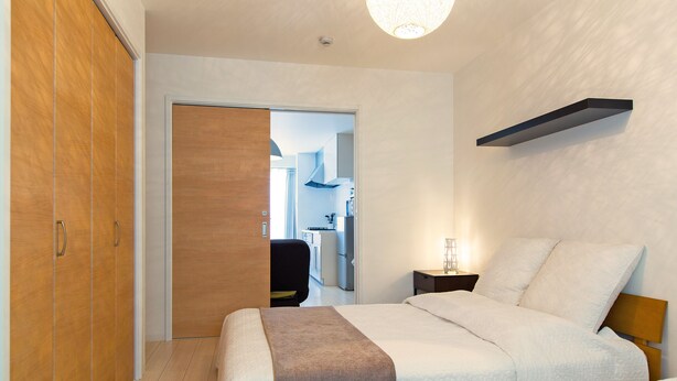 A bedroom with a bed, bedside table, and wardrobe. - Grandouce Namba-Nishi (Osaka)