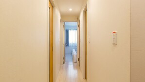 A narrow hallway with light-colored walls and wooden doors. - Grandouce Namba-Nishi (Osaka)