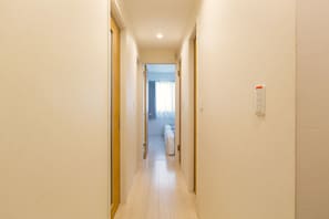 Enter a serene hallway leading to a room with a large window and a comfortable space.
