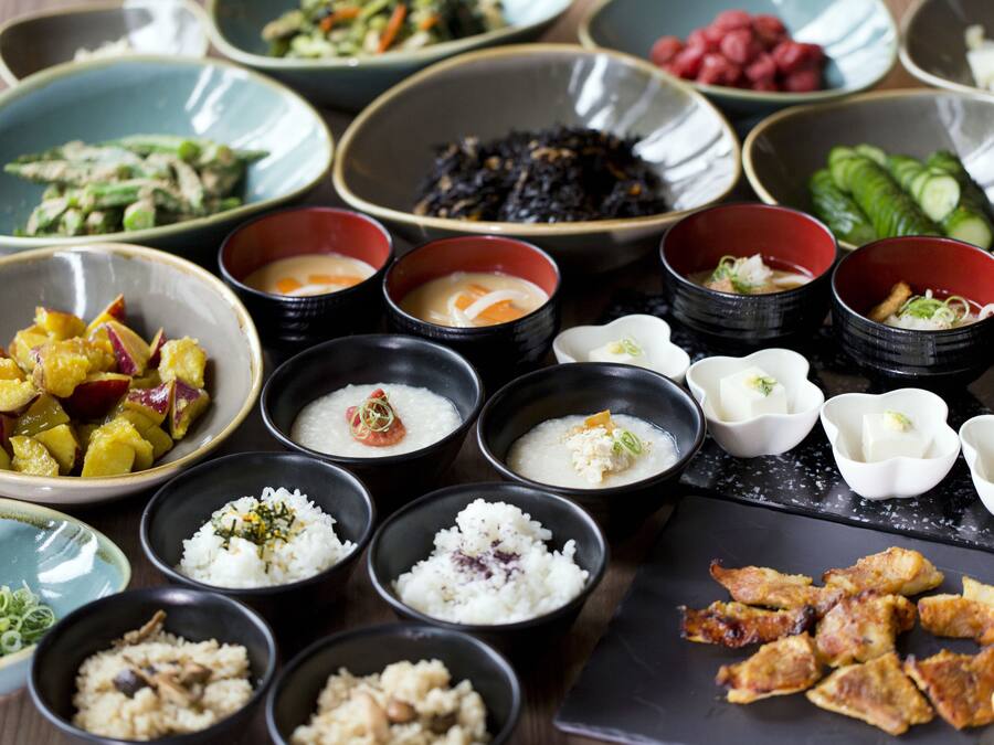 A variety of dishes arranged on a table, including bowls of rice, soup, and vegetables.