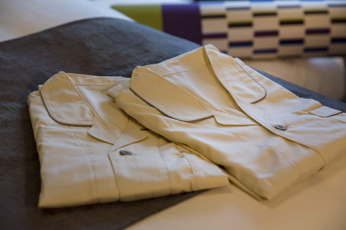A neatly folded beige shirt on a dark grey pillow.