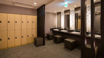 A hotel bathroom with multiple lockers, sinks, and mirrors.