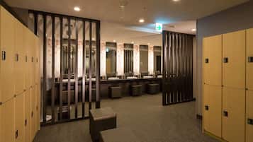 A hotel bathroom with multiple lockers, a mirror, and a fan.