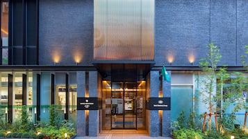Hotel Monterrey's entrance features a modern design with a glass door and metal frame, flanked by illuminated signs.