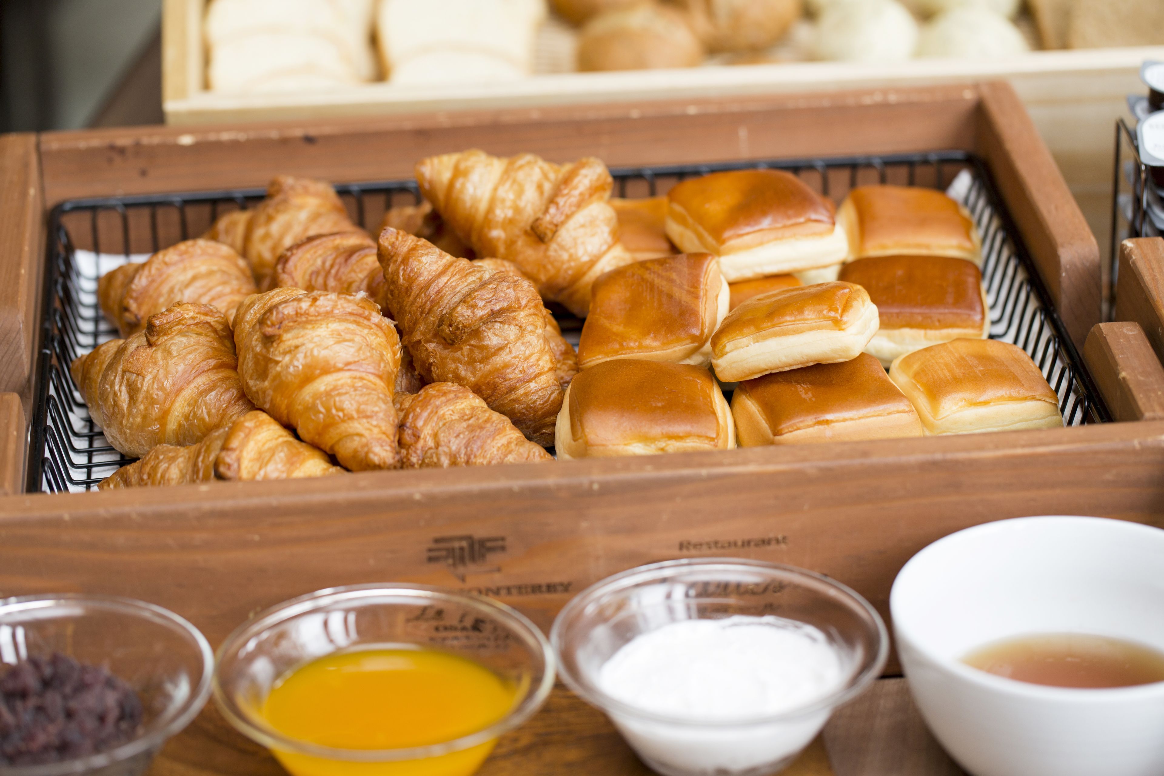 A wooden tray with various baked goods and small bowls of condiments.
