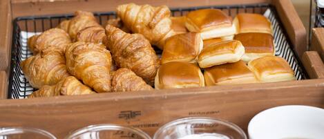 A wooden tray with various baked goods and small bowls of condiments.