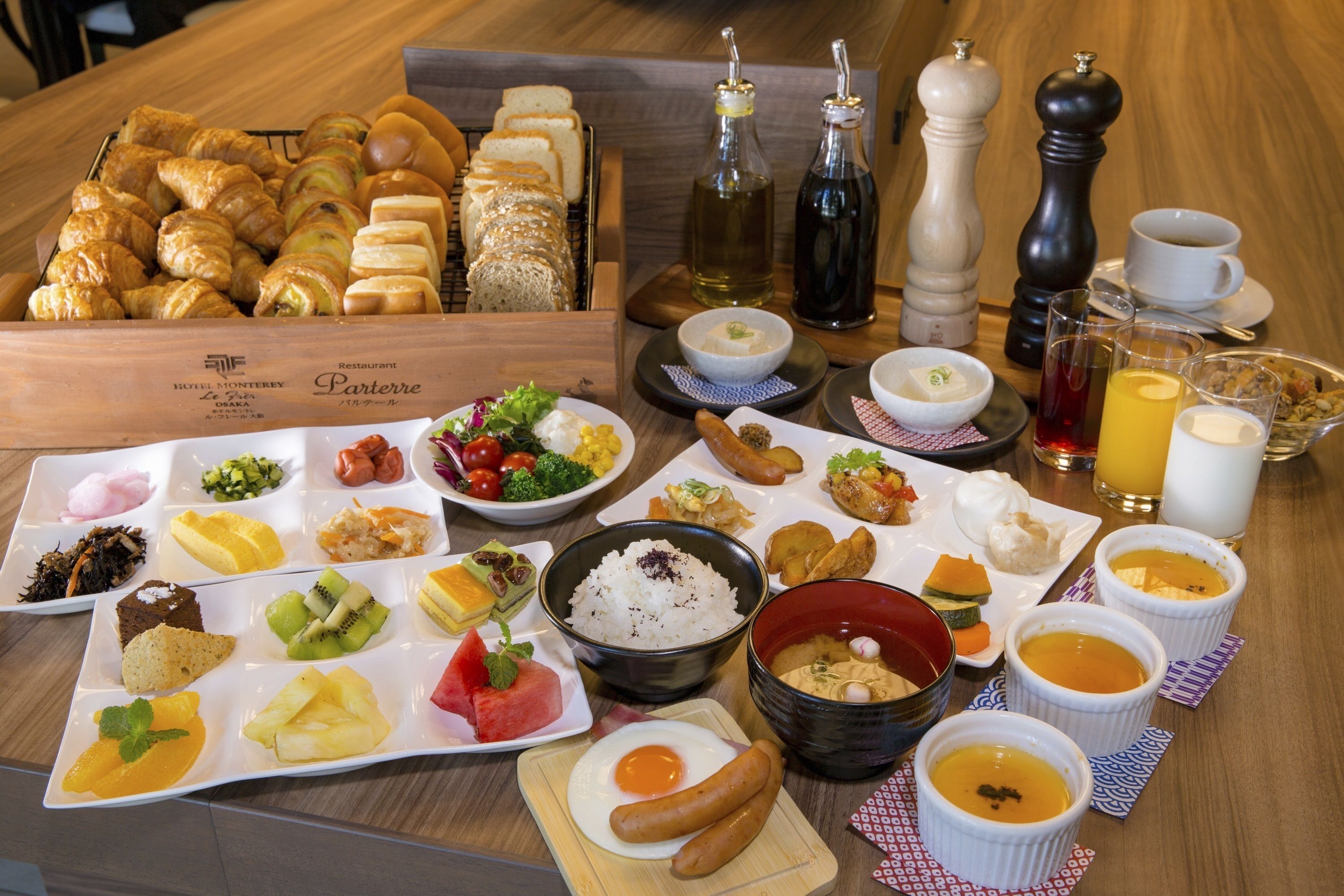 A breakfast buffet with various dishes including croissants, bread, fruits, and beverages.
