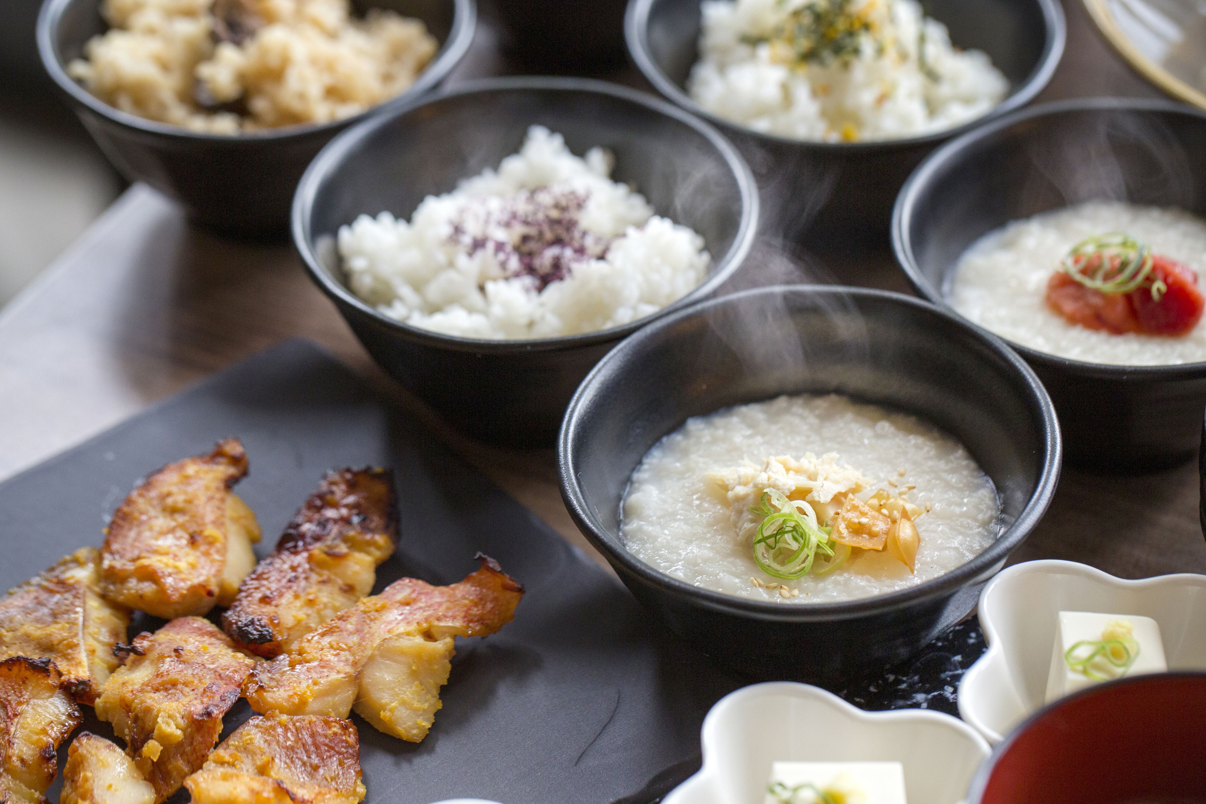 Diversos pratos, incluindo um pote de arroz, um pote de sopa e carne grelhada.