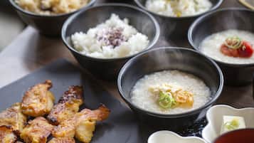 Diversos pratos, incluindo um pote de arroz, um pote de sopa e carne grelhada.