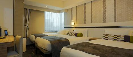 Quarto de hotel com duas camas, uma escrivaninha e uma cadeira.