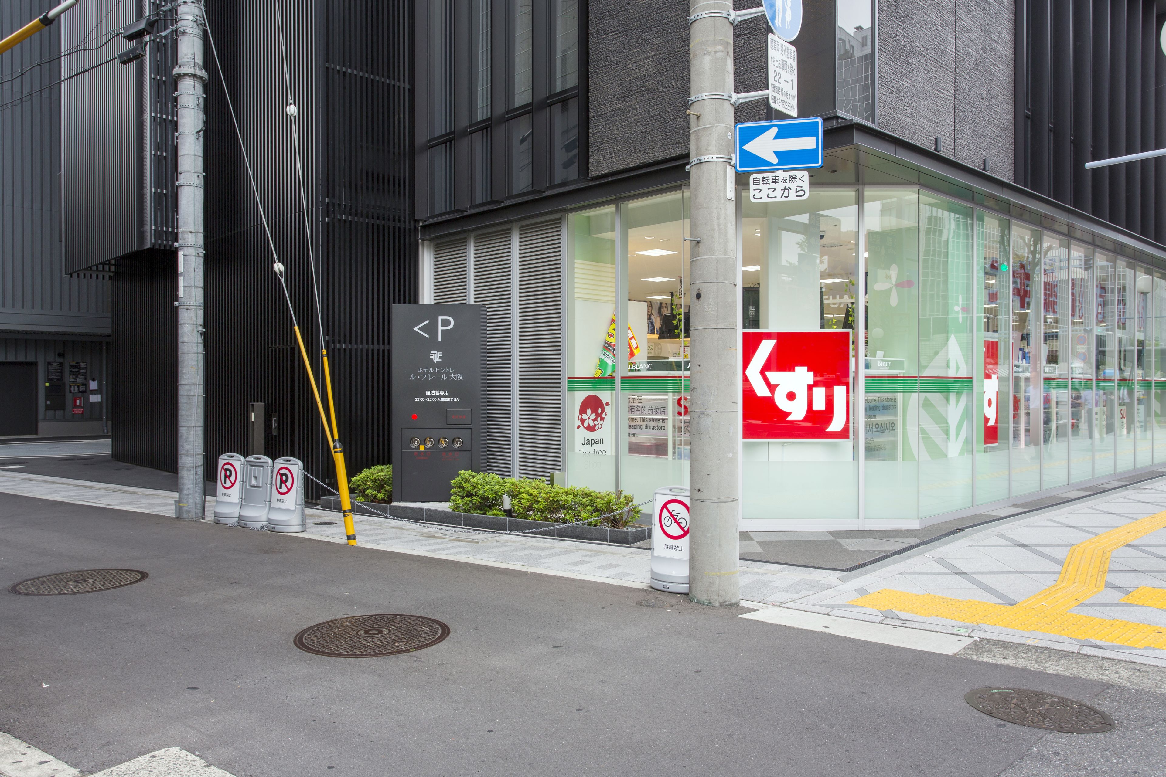 A building with a glass facade, a no parking sign, and a directional sign.