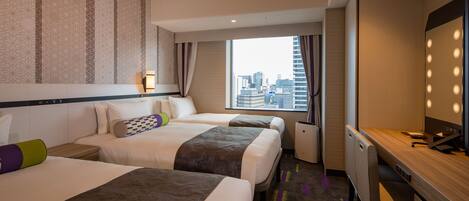 A hotel room with two beds, a desk, a mirror, and a window with a city view.