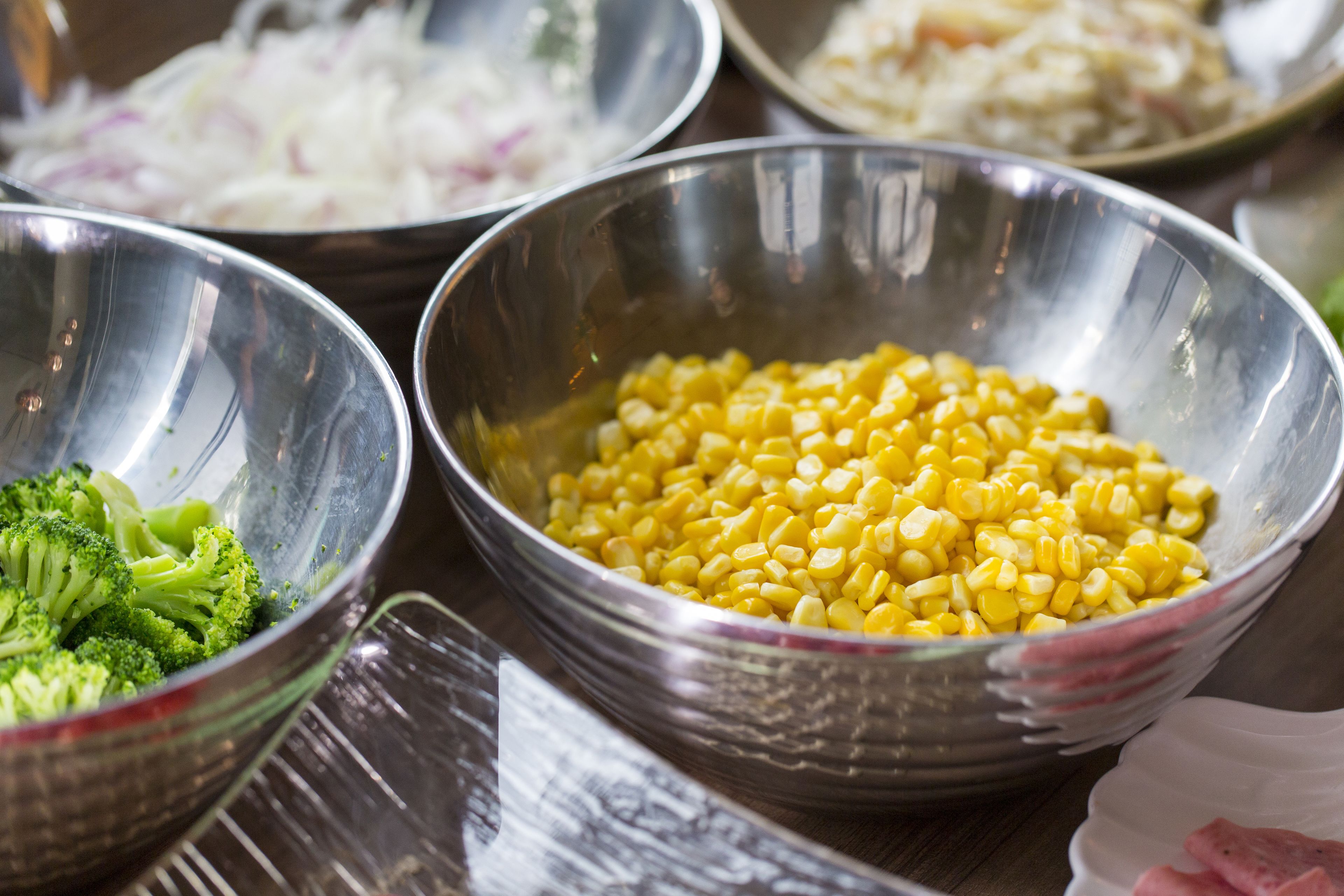 A table with several metal bowls containing different food items.