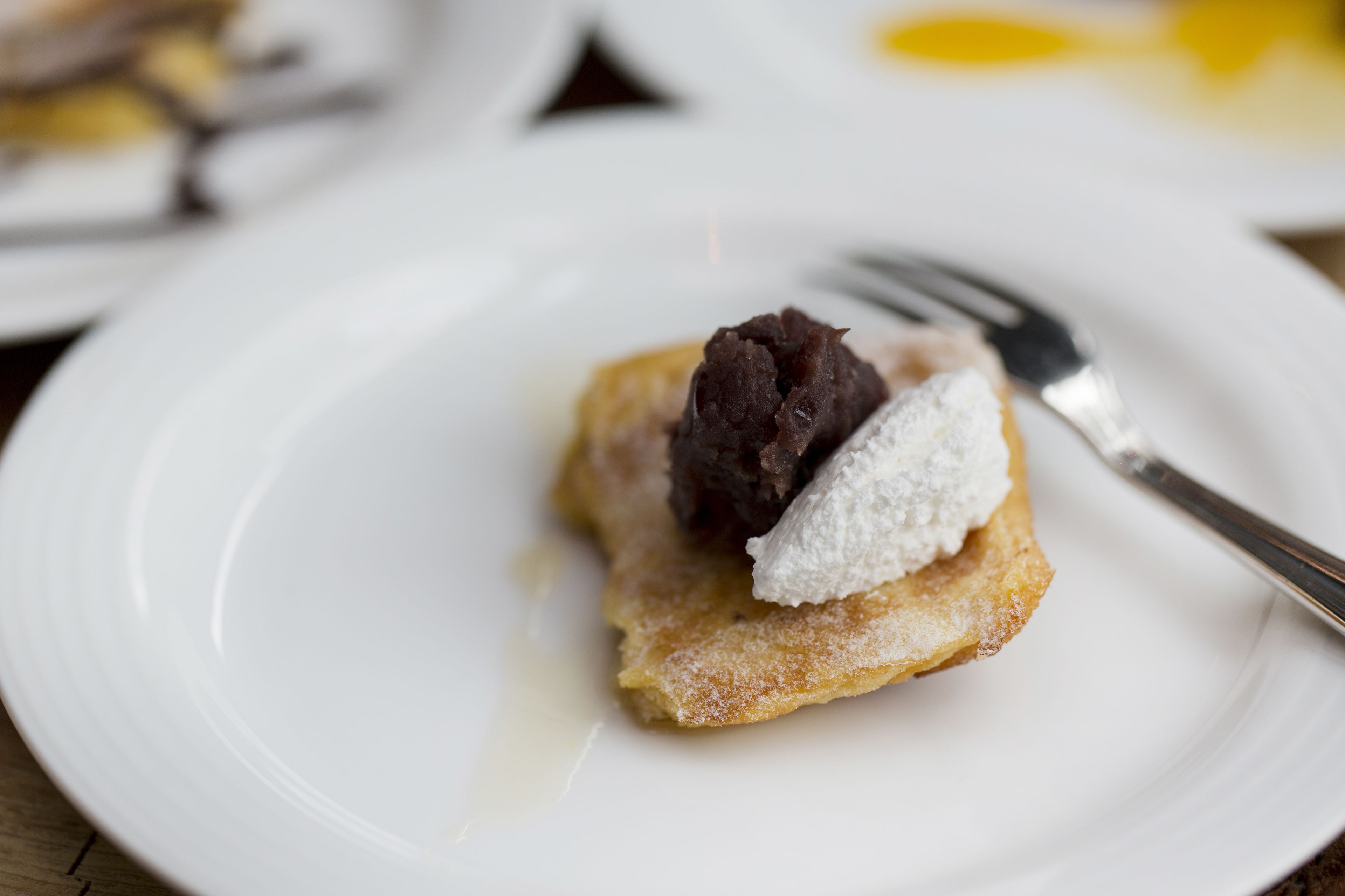 A dessert on a white plate with powdered sugar and a fork.