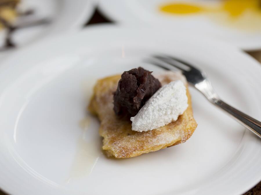 Un postre en un plato blanco con azúcar glas y un tenedor.
