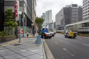 Una calle urbana con edificios altos, un camión azul y una furgoneta amarilla de reparto.