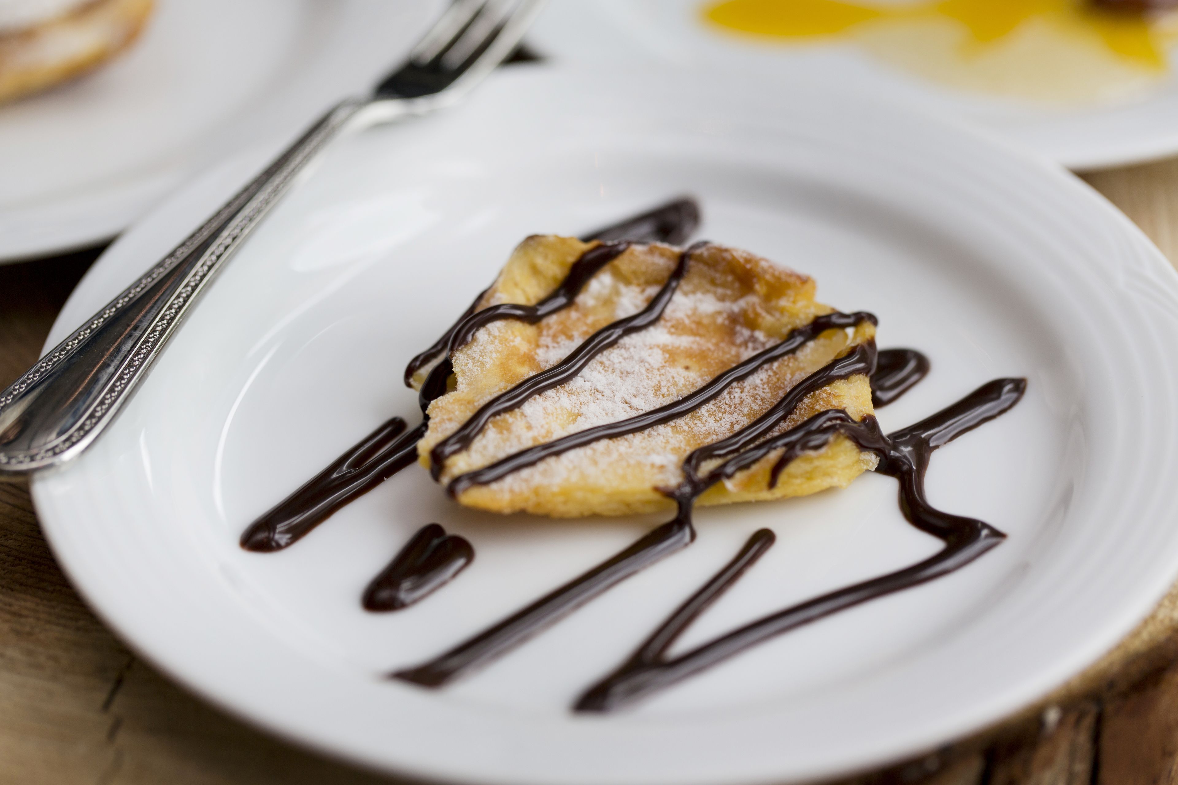 A dessert on a white plate with chocolate drizzle.
