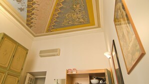 A room with a decorative ceiling, a wooden cabinet, and a shelf with dishes. - Affitta Camere Via Veneto (Rome)