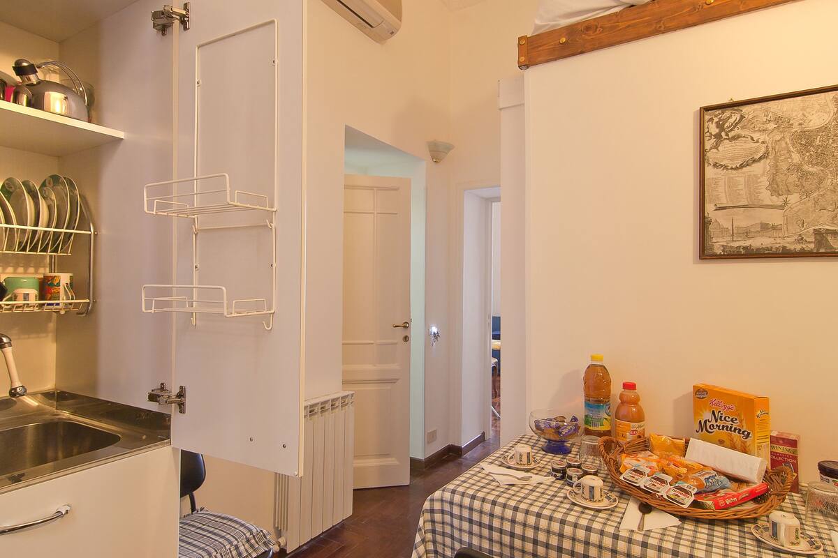 A compact kitchen with a sink, a white door, and a dining area with a table set for breakfast.