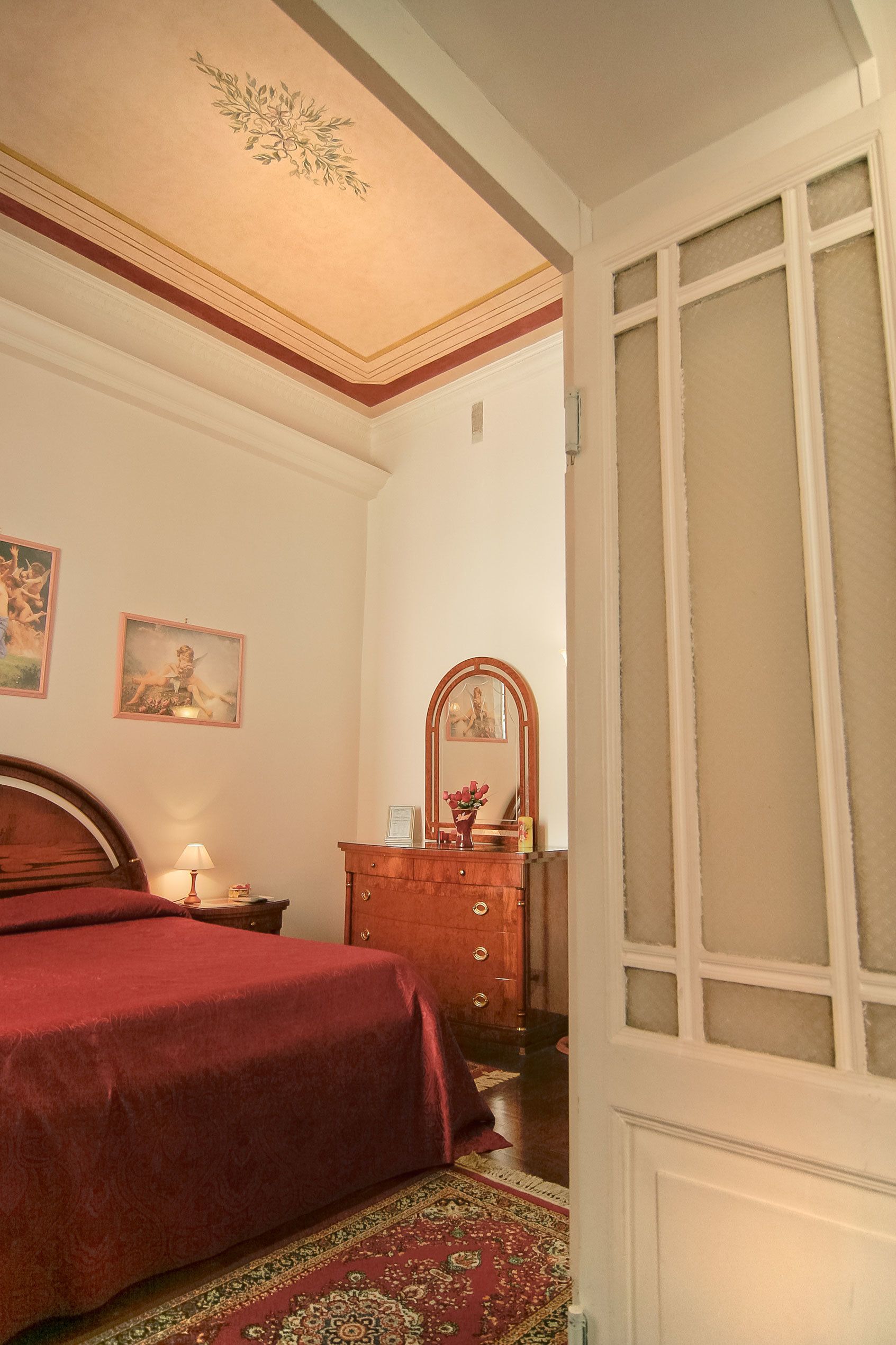 A bedroom with a bed, a dresser, a mirror, and a door with frosted glass panels.