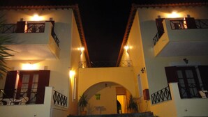A two-story building with a central archway leading to a door. - Victorias Rooms (Chios)