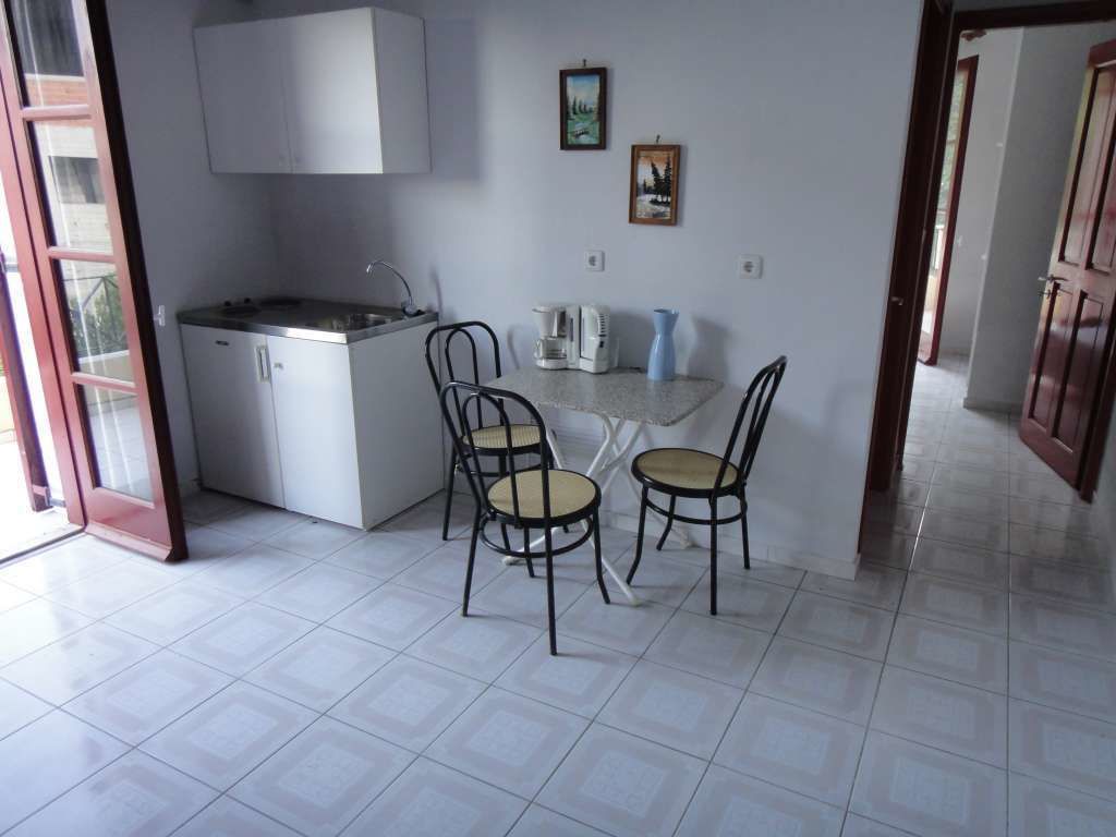 Una cocina compacta con estufa integrada, una pequeña mesa de comedor con dos sillas y una máquina de café.
