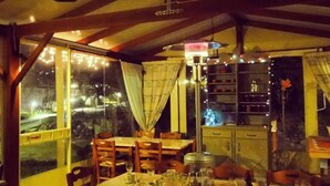 A dining area with a table set for four, wooden chairs, and a hanging light fixture. - Victorias Rooms (Chios)